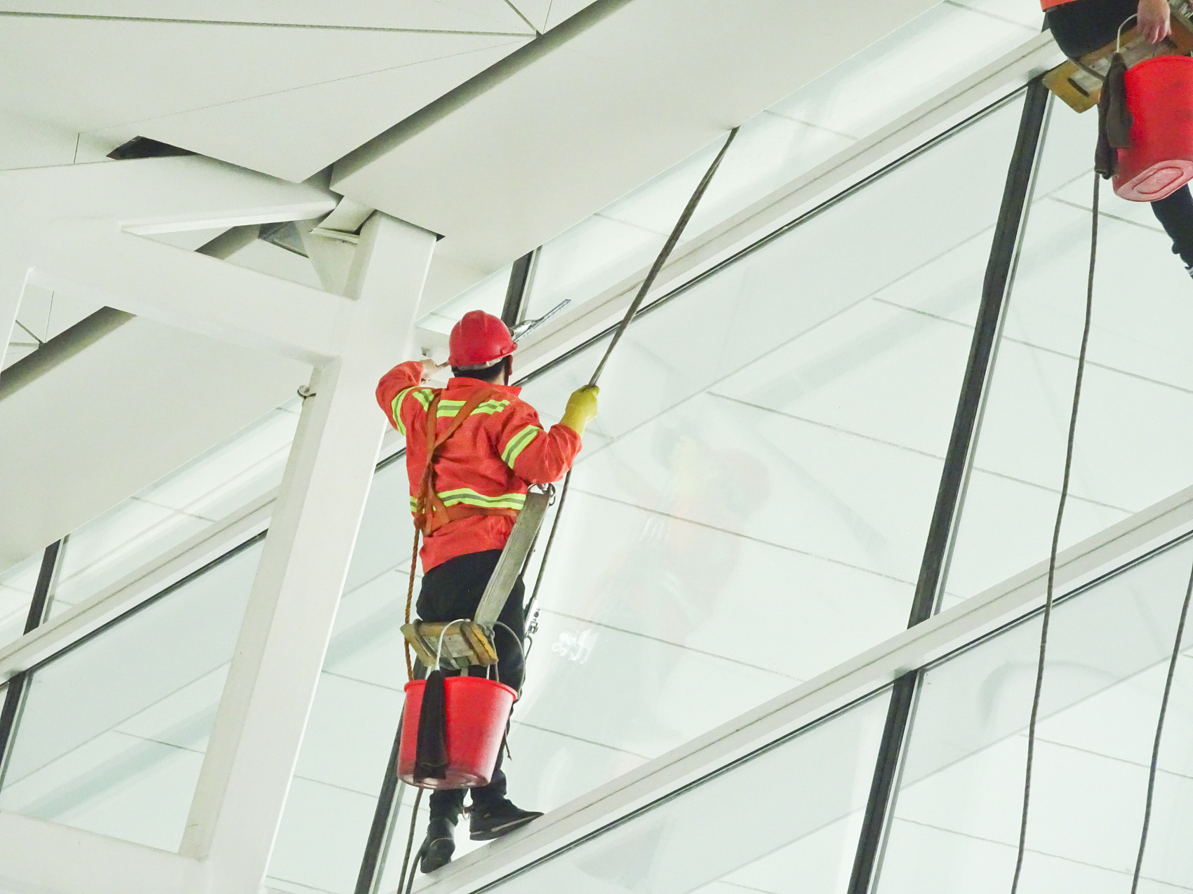 Wuhan, China - December 28, 2018 Workers at altitude in climbing equipment wash the windows at the airport.jpg